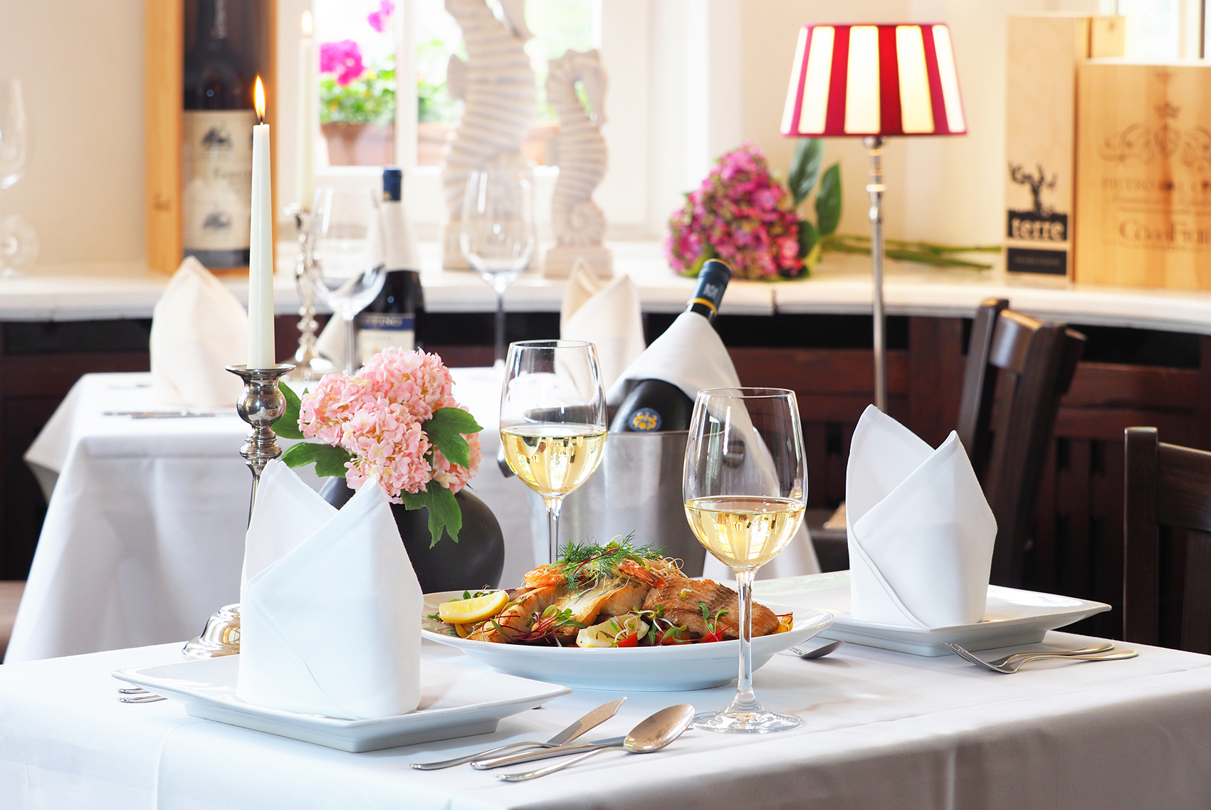 Ein mit Speisen und Wein gedeckter Tisch im Reustaurant der Strandvillen